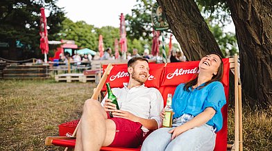 Eine Frau und ein Mann entspannen in einem Liegestuhl am Biergarten des Tempelhofer Felds