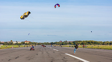 Windsport-Kites über der Asphalt-Landebahn des Tempelhofer Feldes